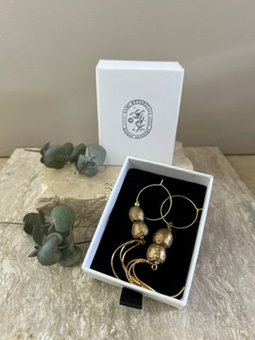 Gold earrings in a box with a white branded box on a marble surface