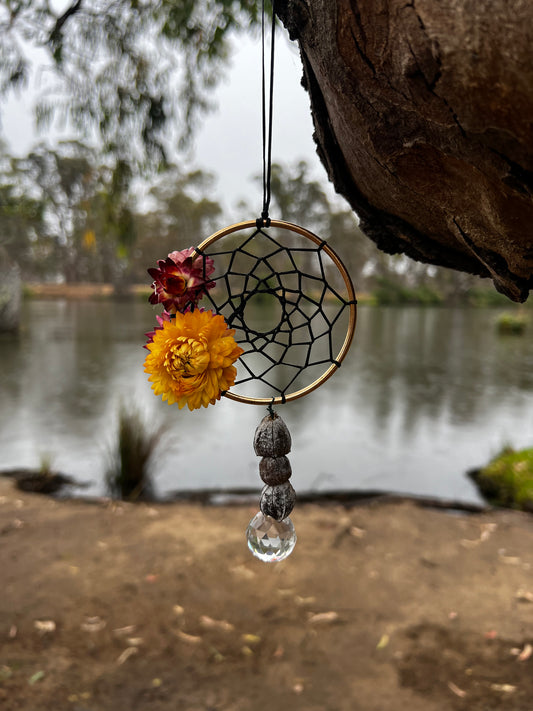 handmade dreamcatcher hanging on a tree with flowers and gumnuts