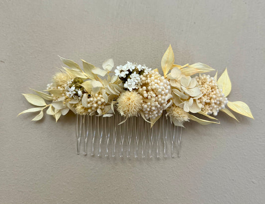 Floral hair comb with dried flowers and leaves on a plain background