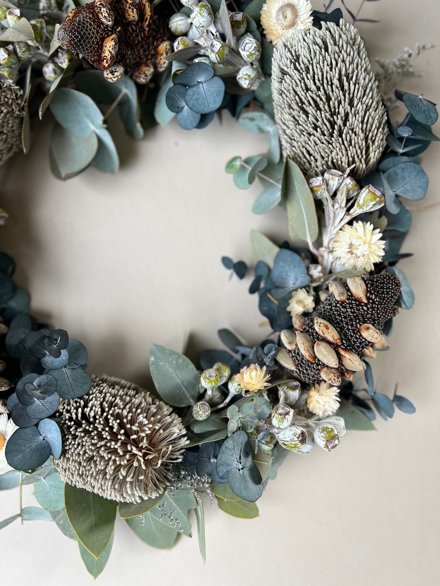 handmade australian wreath using natural australian flowers. Hanging on white wall