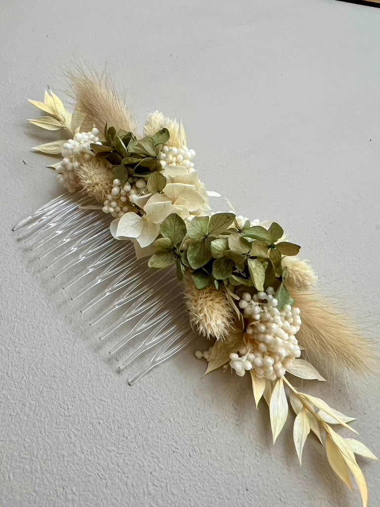 Decorative hair comb with greenery and berries on a plain background