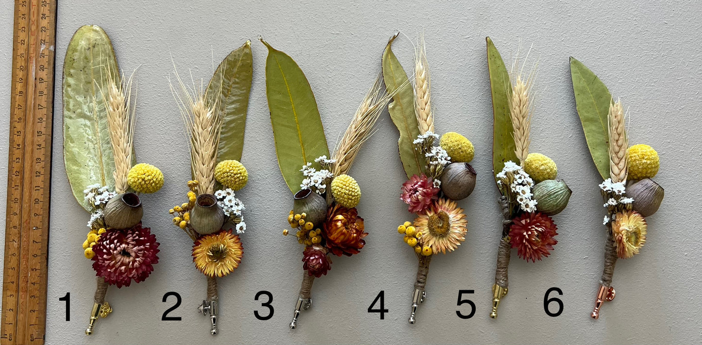 Set of six floral boutonnieres with a ruler for scale on a gray background