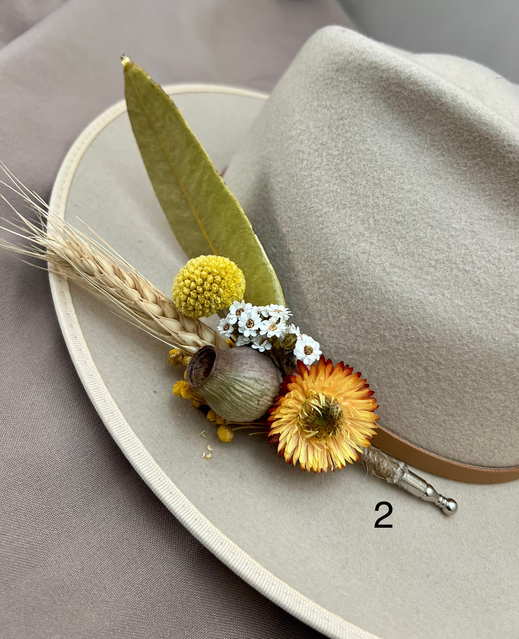 Floral boutonniere on a hat with a gray background