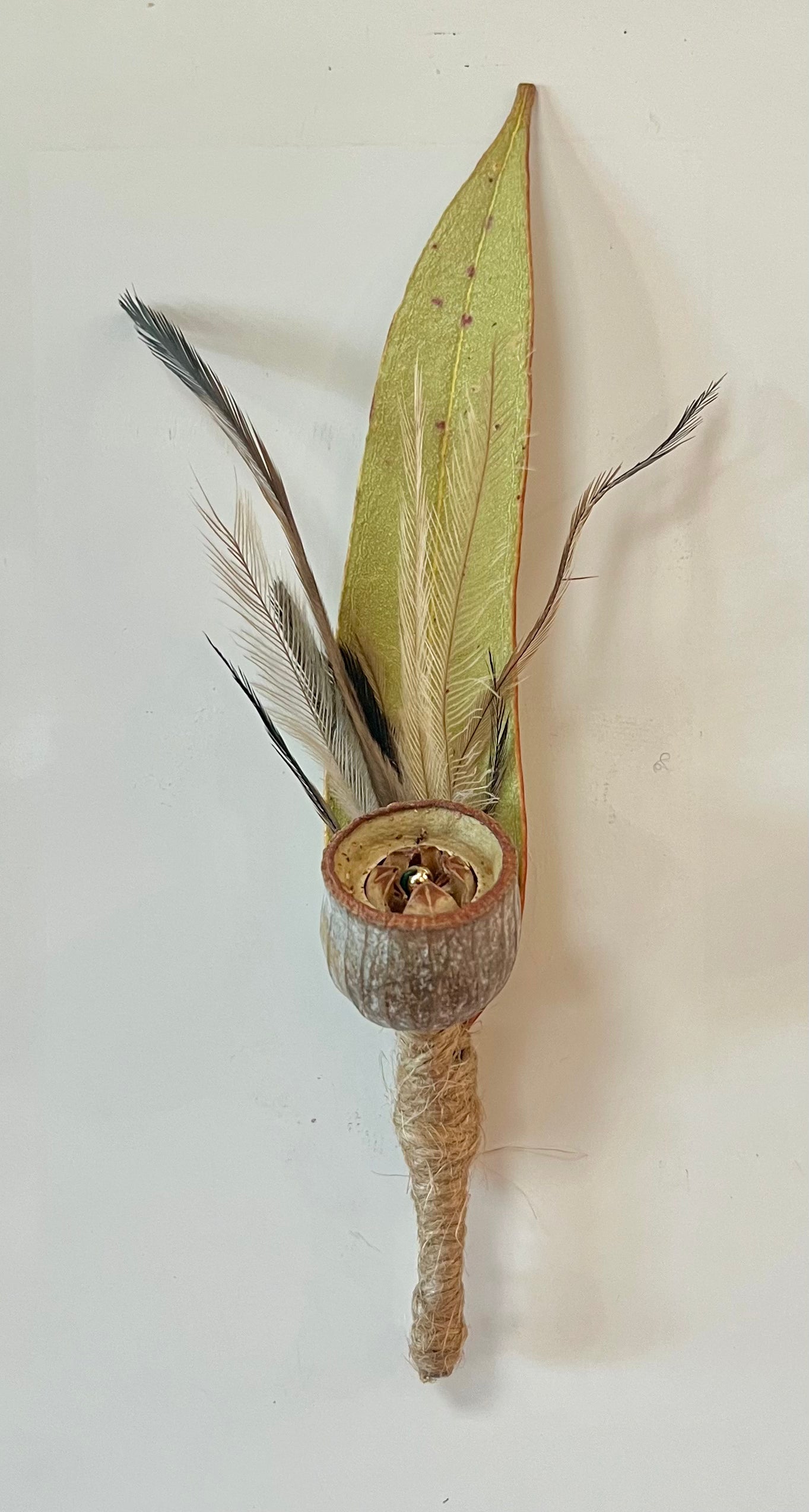 Decorative magnet boutonniere with green leaf and feather on a white background