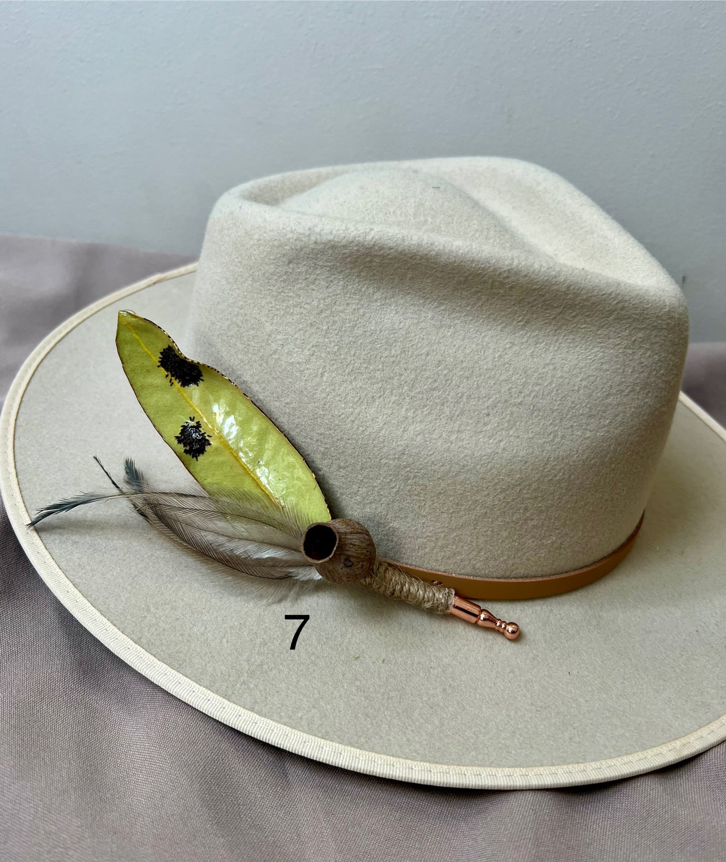 White hat with feather detail on a gray surface