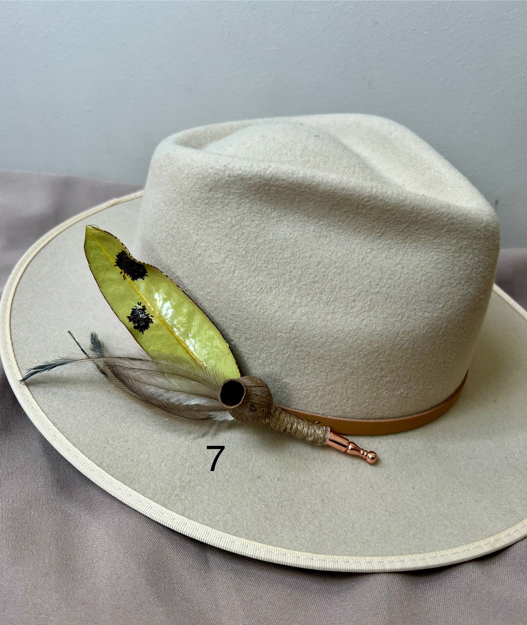 White hat with feather detail on a gray surface