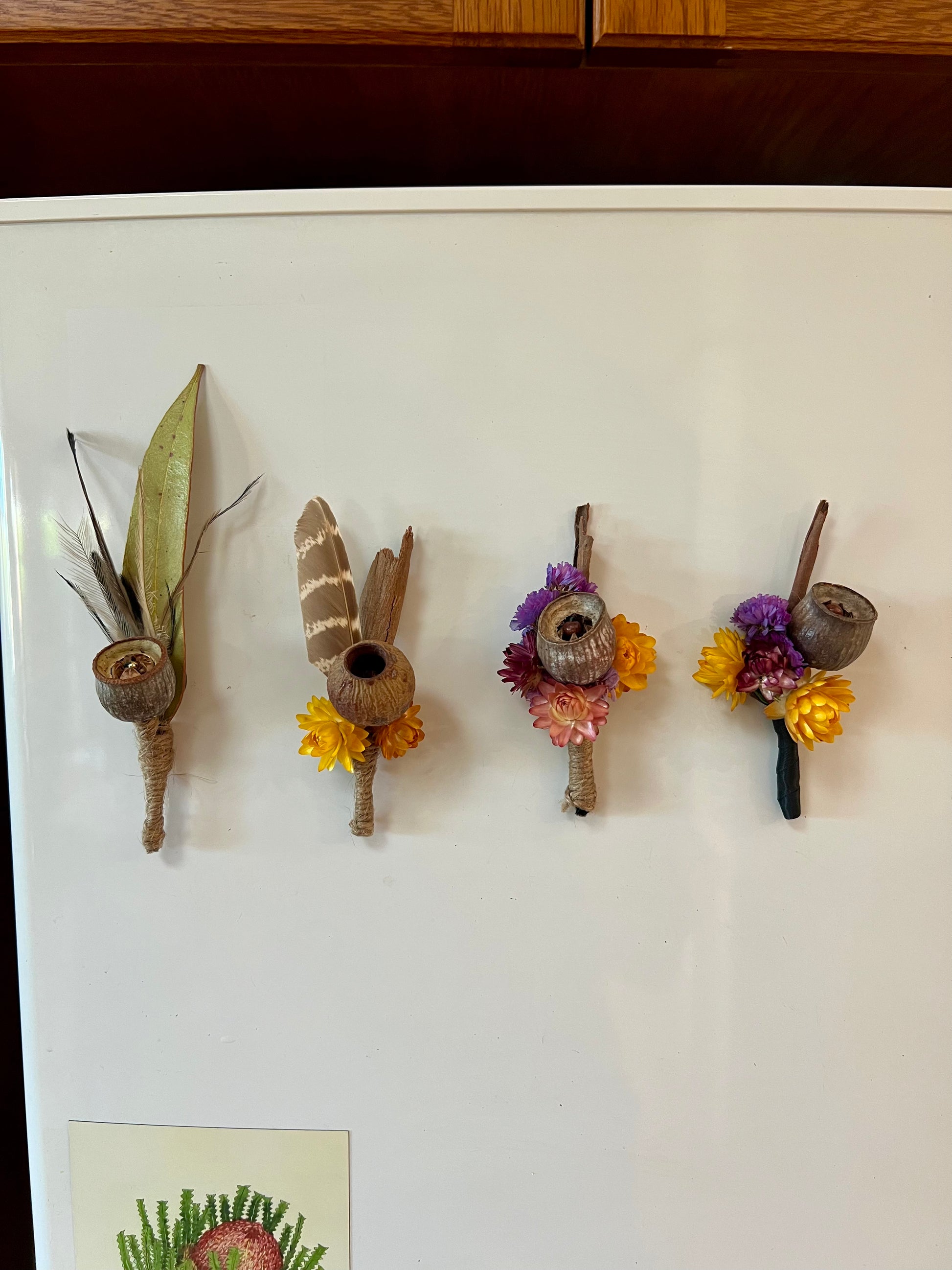 Four decorative magnet boutonnieres with natural australian elements on a white surface.