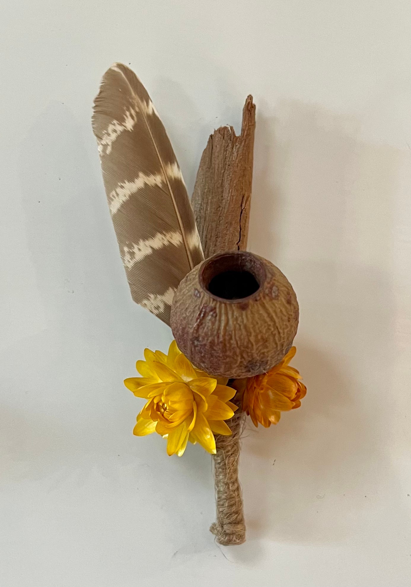Decorative boutonniere fridge magnet with acorn, feather, and yellow flower on a white background